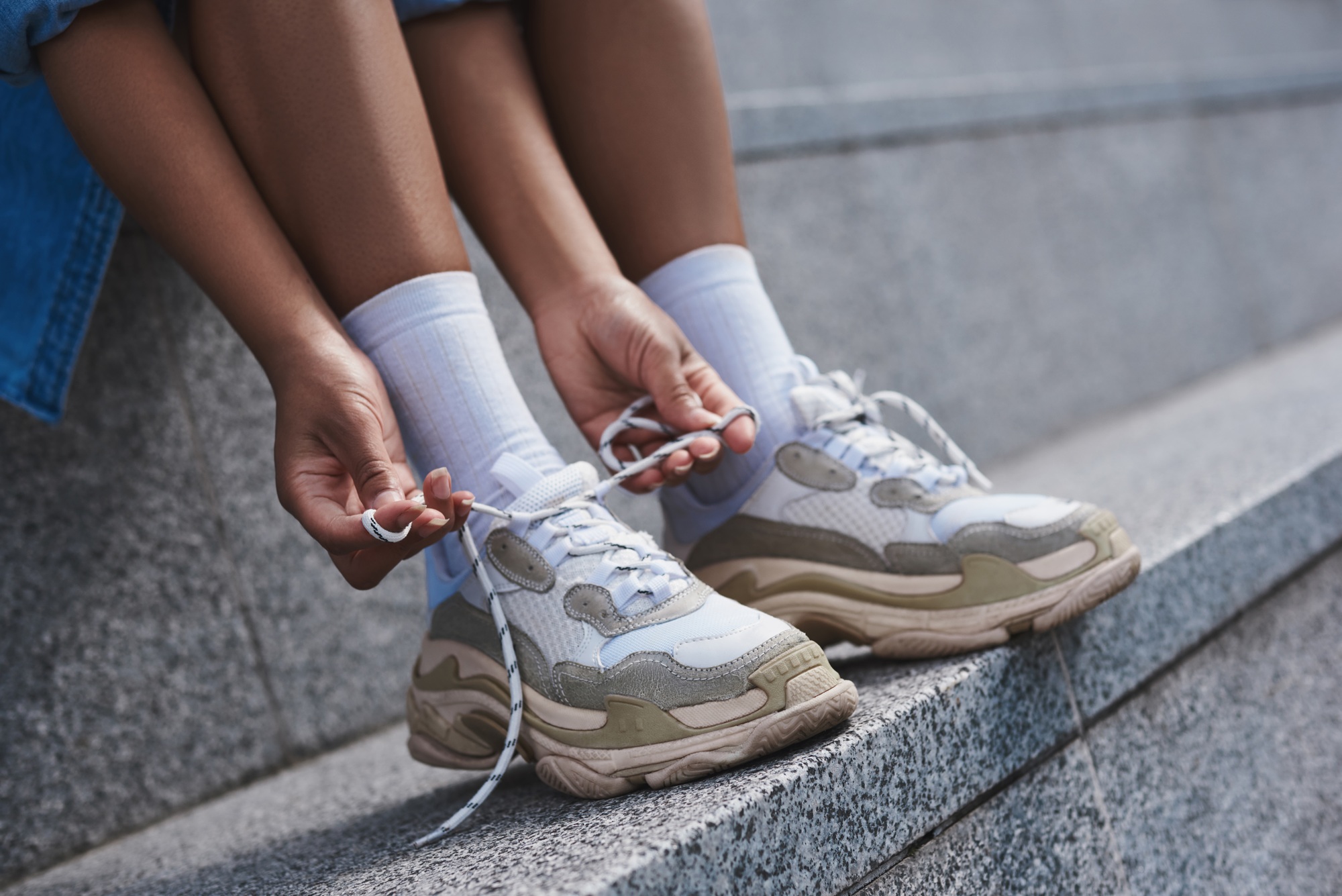 Young woman free style on the street sitting on stairs tying sho